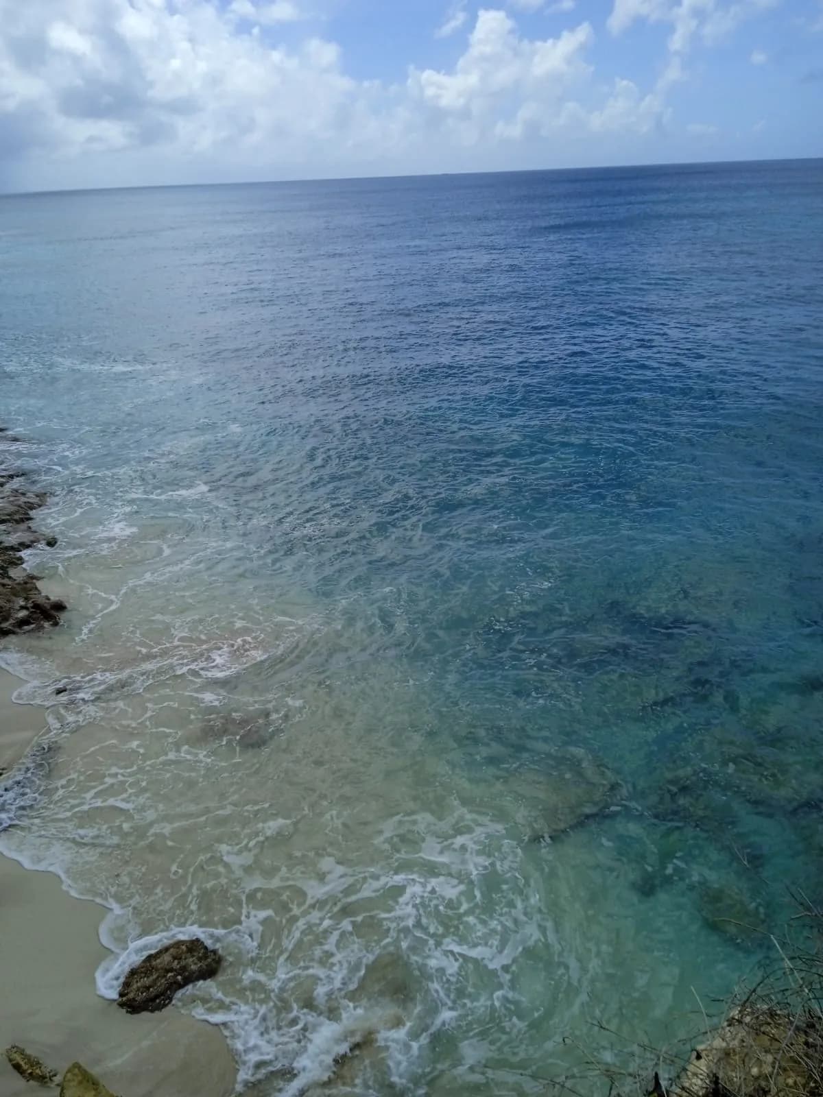 Clear rocky shoreline and calm water at Maho Beach between plane landings
